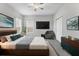 Modern bedroom with a ceiling fan, bedside table, television, and gray accent chair at 6125 Anise Dr, Sarasota, FL 34238
