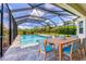 Screened-in pool area with an outdoor dining table and chairs on a stone-paved patio at 6125 Anise Dr, Sarasota, FL 34238