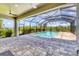 Screened-in pool area with a stone-paved patio and a view of the well-kept backyard at 6125 Anise Dr, Sarasota, FL 34238