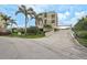 Exterior view shows condo building with mature palm trees, and a parking garage entrance at 6372 Palma Del Mar S Blvd # 503, St Petersburg, FL 33715