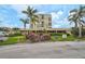 Exterior view shows condo building with mature palm trees, vibrant landscaping, and covered parking at 6372 Palma Del Mar S Blvd # 503, St Petersburg, FL 33715