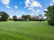 Expansive backyard featuring lush green grass, mature trees, and a screened-in lanai, perfect for outdoor entertaining at 6643 Butlers Crest Dr, Bradenton, FL 34203