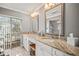 Bathroom with double sinks, granite countertops, white cabinetry, and a view of the landscaped yard through the window at 7804 Broadmoor Pines Blvd, Sarasota, FL 34243