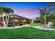 Lush backyard with tropical landscaping, a screened-in lanai, firepit, and seating area at 7913 19Th Avenue W Dr, Bradenton, FL 34209