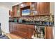 Close-up of the built-in bar area with wood cabinets, black countertop, tile backsplash, and beverage storage at 7913 19Th Avenue W Dr, Bradenton, FL 34209