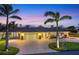Stunning home showcasing a circular driveway, beautiful palms, and illuminated exterior for enchanting evening ambiance at 7913 19Th Avenue W Dr, Bradenton, FL 34209