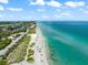 Expansive beach with turquoise waters, clear skies, and a mix of natural dunes and urban development at 8234 Midnight Pass Rd, Sarasota, FL 34242