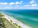 Picturesque beach scene with clear turquoise waters, white sand, and scattered beachgoers under a blue sky at 8234 Midnight Pass Rd, Sarasota, FL 34242