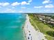 Scenic beach with crystal-clear water, white sand, and a mix of beachgoers, vegetation, and buildings at 8234 Midnight Pass Rd, Sarasota, FL 34242