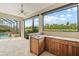 Covered patio features an outdoor kitchen, bar, and views of the pool and lush greenery at 8930 Bloomfield Blvd, Sarasota, FL 34238