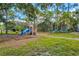 Community playground featuring slides and other play equipment amidst lush landscaping and mature trees at 8930 Bloomfield Blvd, Sarasota, FL 34238