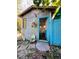 Exterior view of the shed showing colorful floral decorations, an adjacent blue fence, and a cozy outdoor space at 1019 10Th W Ave, Bradenton, FL 34205