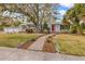 Charming single-story home featuring a well-manicured lawn, mature trees, and a welcoming red front door at 102 28Th W St, Bradenton, FL 34205