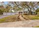 Charming home with a red door, surrounded by mature trees and a well-kept lawn at 102 28Th W St, Bradenton, FL 34205