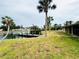 Waterfront backyard with a private dock, lush lawn, and mature palm trees enhance this property's appeal at 104 Pops Ln, Nokomis, FL 34275