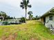 Spacious backyard with a private dock, lush lawn, mature palm trees, and convenient outdoor storage at 104 Pops Ln, Nokomis, FL 34275