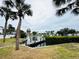 Waterfront backyard view featuring a private dock, lush lawn, and mature palm trees enhances this property at 104 Pops Ln, Nokomis, FL 34275