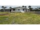 Backyard of home with a chainlink fence, green grass, and overcast sky at 104 Pops Ln, Nokomis, FL 34275