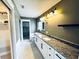 Bathroom features a double vanity with granite countertops and modern lighting fixtures at 104 Pops Ln, Nokomis, FL 34275