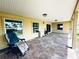 A large patio with yellow walls, a brown tile floor, windows, and sliding glass doors at 104 Pops Ln, Nokomis, FL 34275