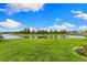 Scenic backyard with lush lawn and serene pond views under a bright blue sky at 10868 Sun Drop St, Venice, FL 34293