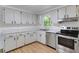 Well-lit kitchen with white cabinets, stainless steel appliances, and a view of the backyard at 112 E Marland Ct, Nokomis, FL 34275