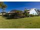 Wide shot of a yard featuring a screened lanai, mature landscaping, and green grass at 1279 Vermeer Dr, Nokomis, FL 34275