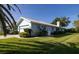 Light-blue home exterior featuring a well-kept lawn and tropical landscaping at 1279 Vermeer Dr, Nokomis, FL 34275