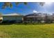 Spacious backyard featuring a screened lanai, lush green lawn, and some shrubs at 1279 Vermeer Dr, Nokomis, FL 34275