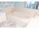 Close-up view of the bathtub area with white marble and patterned blue wallpaper in the bathroom at 1279 Vermeer Dr, Nokomis, FL 34275