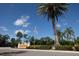 Entrance to Sorrento Woods featuring lush landscaping, mature palm trees, and an American flag at 1279 Vermeer Dr, Nokomis, FL 34275