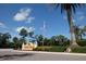 Entrance to Sorrento Woods featuring lush landscaping, mature palm trees, and an American flag at 1279 Vermeer Dr, Nokomis, FL 34275