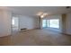 Empty living room featuring tan carpet, neutral walls, ceiling fan, and sliding glass doors at 1279 Vermeer Dr, Nokomis, FL 34275