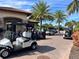 Golf carts lined up outside clubhouse with palms and brick pavers on a sunny day at this desirable golf community at 13108 Torresina Ter, Bradenton, FL 34211