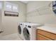 Well-lit laundry room featuring a washer and dryer, overhead shelving, and a decorative 'Wash, Dry, Fold, Repeat' sign at 13108 Torresina Ter, Bradenton, FL 34211