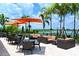 Inviting outdoor seating by the water features cushioned sofas, tables, and chairs under orange umbrellas at 13108 Torresina Ter, Bradenton, FL 34211