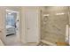 Modern tiled shower with glass door and seat for comfort, adjoining a well-lit bedroom with plantation shutters at 13108 Torresina Ter, Bradenton, FL 34211