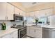 Well-lit kitchen with white cabinets, stainless steel appliances, and quartz countertops overlooking the living area at 2124 N Tamiami Trl # 108, Sarasota, FL 34234