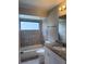 Bathroom features a tiled tub and shower, granite vanity, and a window bringing in natural light at 2475 Wood Oak Dr, Sarasota, FL 34232
