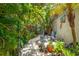 Charming backyard features lush greenery, a quaint stone pathway, a wrought iron trellis and a relaxing outdoor seating area at 2630 Bucida Dr, Sarasota, FL 34232