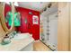 The bathroom features vibrant red walls, colorful accents, and a walk-in shower at 2630 Bucida Dr, Sarasota, FL 34232