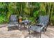 Enjoy outdoor seating featuring comfortable chairs and a charming table with unique stone decorations, shaded by palm trees at 2630 Bucida Dr, Sarasota, FL 34232