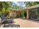 Relax on this brick paved patio with comfortable lounge chairs, a decorative stone accent, and lush tropical landscaping at 2630 Bucida Dr, Sarasota, FL 34232