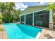 Relaxing outdoor pool area featuring clear blue water and screened in patio with comfortable seating and lush palm trees at 2630 Bucida Dr, Sarasota, FL 34232