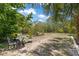 View of a landscaped backyard with a small table and chairs beneath palm and leafy trees at 3500 Liberty St, Port Charlotte, FL 33948