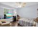 Cozy bedroom with a large window, ceiling fan, and an entertainment center with a television at 3500 Liberty St, Port Charlotte, FL 33948