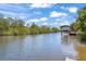 Scenic view of a wide canal with a boat under a covered dock surrounded by lush, green trees at 3500 Liberty St, Port Charlotte, FL 33948
