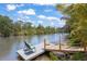 View of a dock with two chairs and a wooden walkway along a canal with lush vegetation at 3500 Liberty St, Port Charlotte, FL 33948