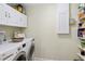 Bright laundry area features front load washer/dryer set and upper white cabinets for storage at 3500 Liberty St, Port Charlotte, FL 33948