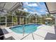 The kidney-shaped pool features a screened enclosure, poolside seating, and well-manicured landscaping at 3500 Liberty St, Port Charlotte, FL 33948